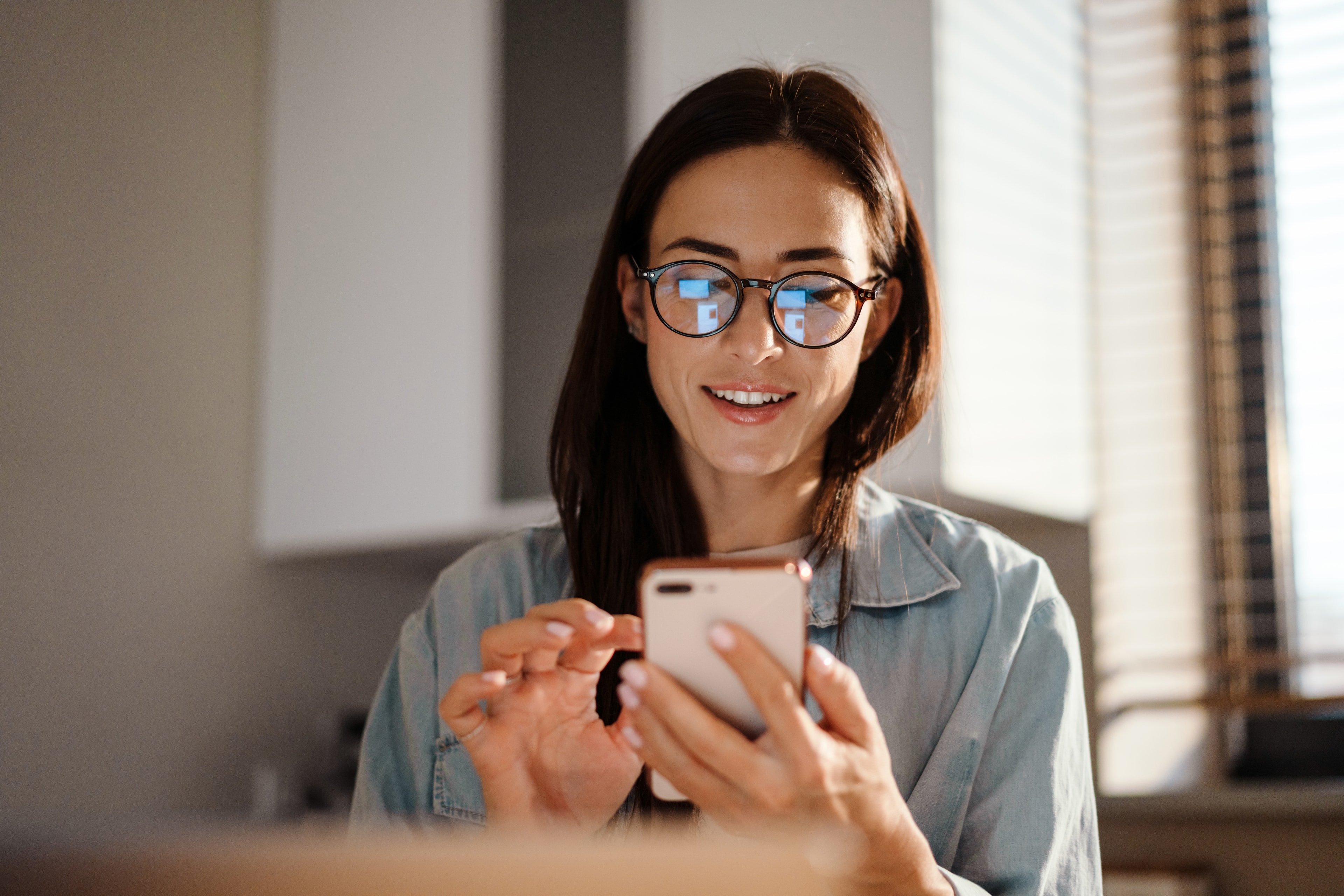 A Direct Payment employer checking her phone in her kitchen at home